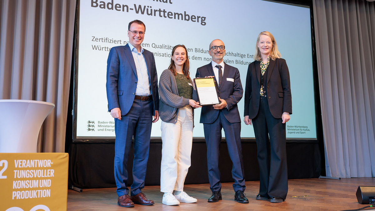 Umweltministerin Thekla Walker MdL und Kultusstaatssekretär Volker Schebesta MdL stehen zusammen mit einer Frau und einem Mann auf einer Bühne. Sie lächeln alle in die Kamera, die Umweltministerin und Vertreter des Naturparks Stromberg-Heuchelberg halten ein eingerahmtes BNE-Zertifikat.