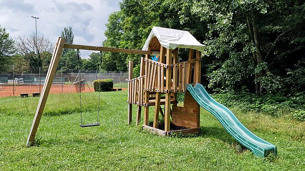 Spielturm mit Rutsche auf dem Rasen des Vereinsgeländes des TC Besigheim.