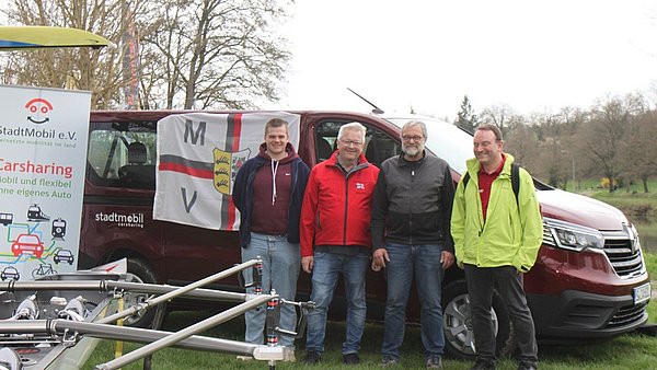 Vier Mitglieder des Marbacher Rudervereins stehen vor einem großen Van und lächeln