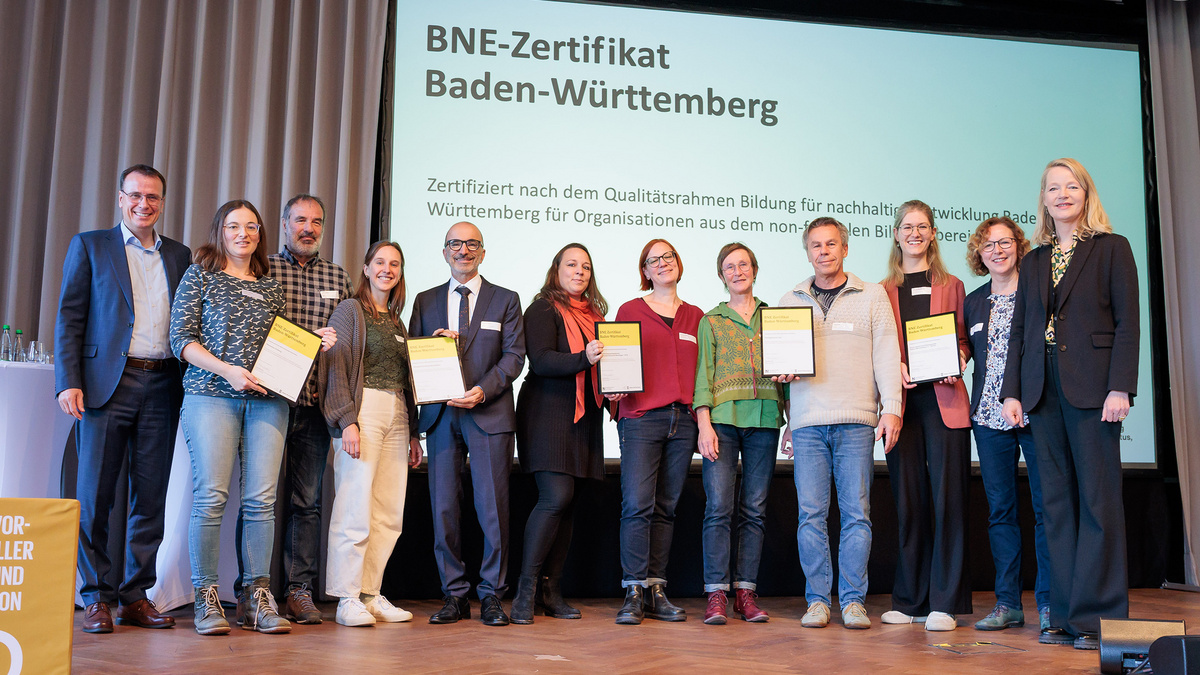 Die Empfängerinnen und Empfänger der BNE-Zertifikate stehen gemeinsam mit der Umweltministerin Thekla Walker und Staatssekretär im Kultusministerium Volker Schebesta stehen gemeinsam zum Gruppenbild auf der Bühne des Netzwerkforums BNE-BW 2030.