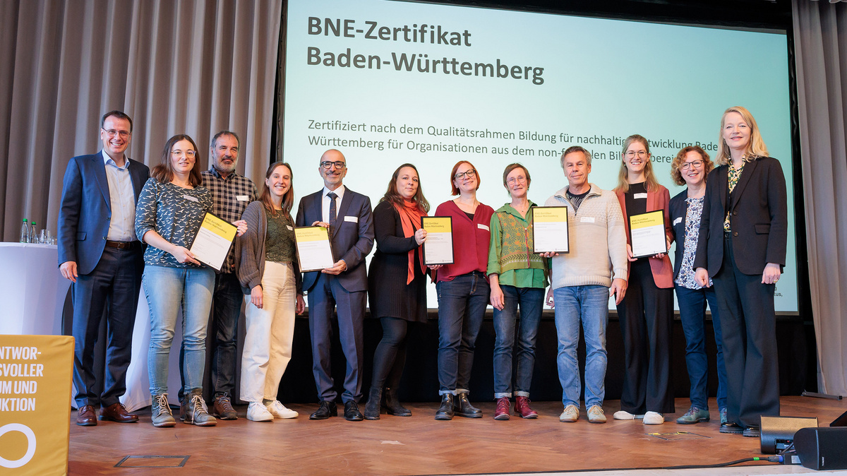 Die Empfängerinnen und Empfänger der BNE-Zertifikate stehen gemeinsam mit der Umweltministerin Thekla Walker und Staatssekretär im Kultusministerium Volker Schebesta stehen gemeinsam zum Gruppenbild auf der Bühne des Netzwerkforums BNE-BW 2030.