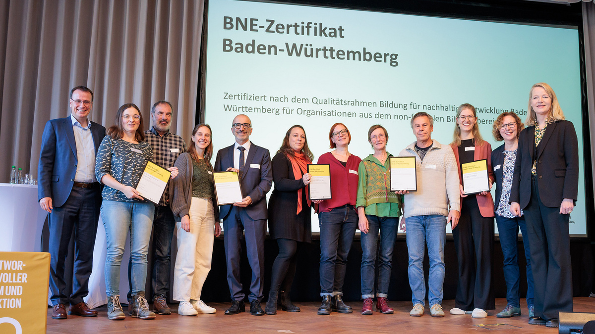 Die Empfängerinnen und Empfänger der BNE-Zertifikate stehen gemeinsam mit der Umweltministerin Thekla Walker und Staatssekretär im Kultusministerium Volker Schebesta stehen gemeinsam zum Gruppenbild auf der Bühne des Netzwerkforums BNE-BW 2030.