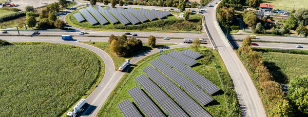 Luftaufnahme von Autobahnauf- und -ausfahrten mit Solarpanelen auf Grünflächen (sogenannte Innenohren). Umgeben von Straßen, Feldern und vereinzelten Gebäuden.